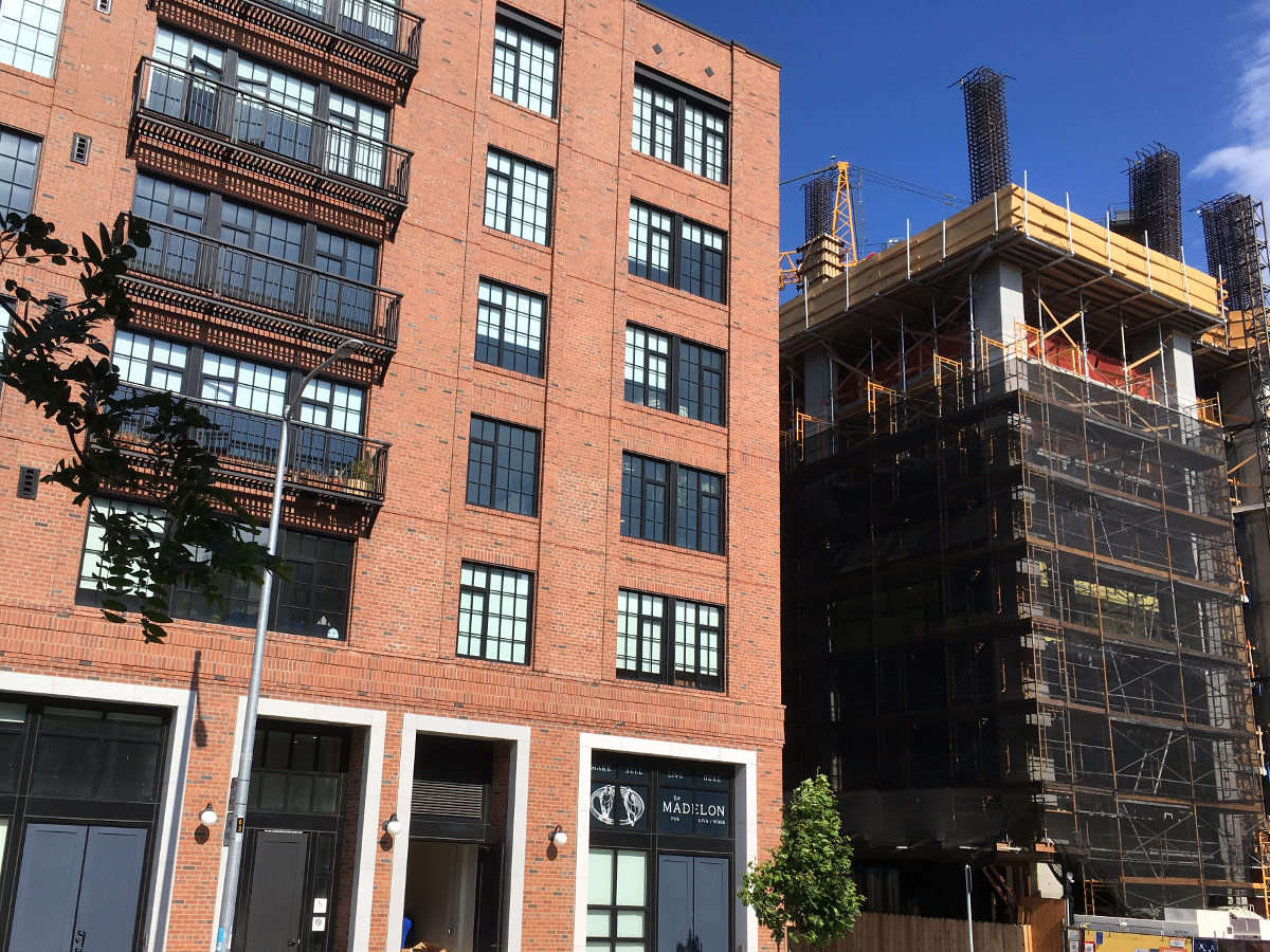 A recently built apartment building stands next to one under construction.