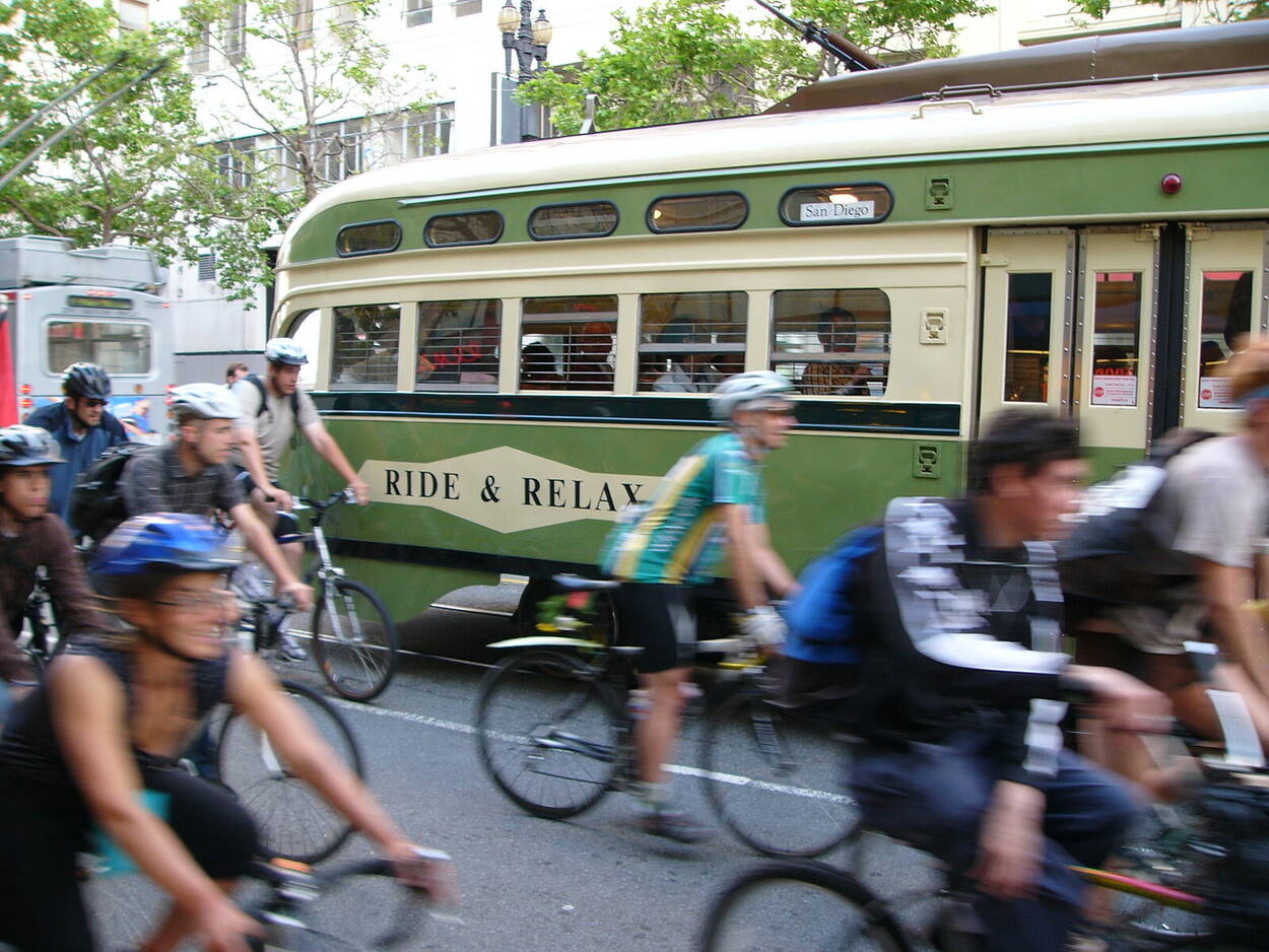 People bike alongside a historic streetcar that says "Ride and Relax" on its livery. Photo by Jef Poskanzer.