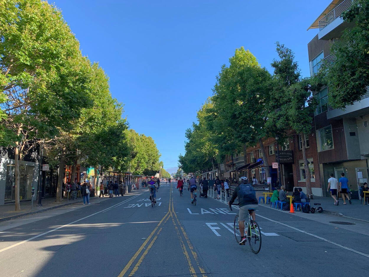 People bike, walk, and dine on a temporarily car-free Valencia Street in San Francisco in July 2022.